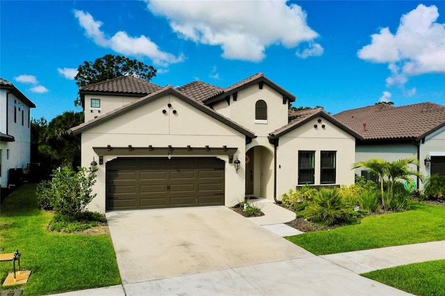 mediterranean / spanish home featuring a garage, a tile roof, concrete driveway, stucco siding, and a front yard