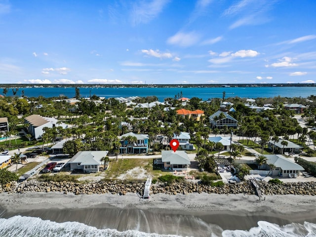 drone / aerial view featuring a water view, a view of the beach, and a residential view