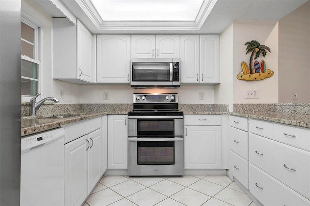 1915 Pebble Beach Ct, Venice, FL 34293 - kitchen with stainless steel appliances, a sink, white cabinets, light stone counters, and light tile patterned floors