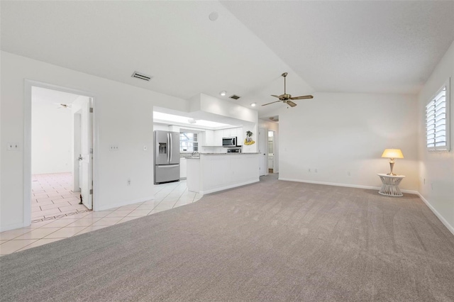 1915 Pebble Beach Ct, Venice, FL 34293 - unfurnished living room with ceiling fan, vaulted ceiling, baseboards, light tile patterned flooring, and light colored carpet