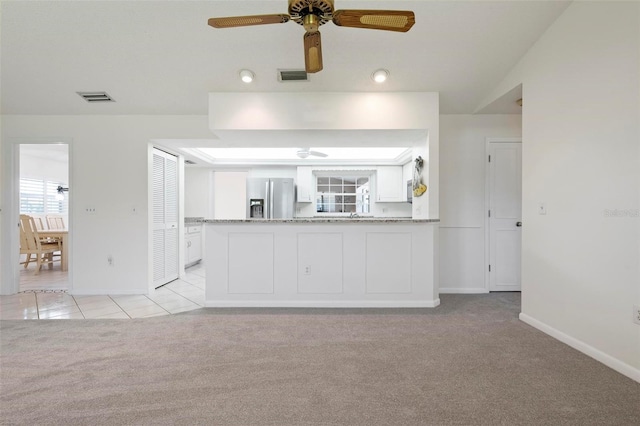 1915 Pebble Beach Ct, Venice, FL 34293 - kitchen with stainless steel fridge with ice dispenser, light carpet, baseboards, white cabinets, and a ceiling fan
