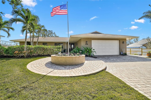 view of front of house with a front yard, decorative driveway, a garage, and stucco siding