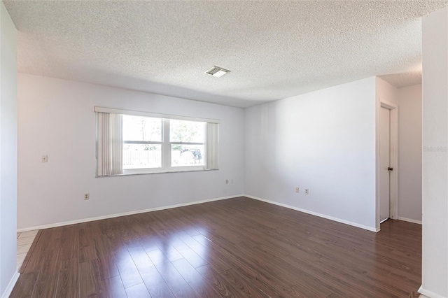 unfurnished room with baseboards, visible vents, dark wood finished floors, and a textured ceiling