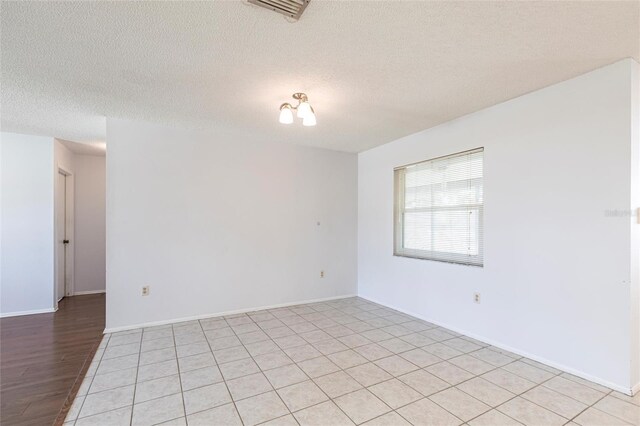 spare room featuring baseboards, visible vents, and a textured ceiling