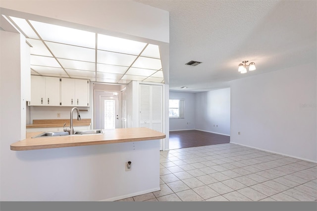 kitchen featuring light countertops, a sink, visible vents, and white cabinetry