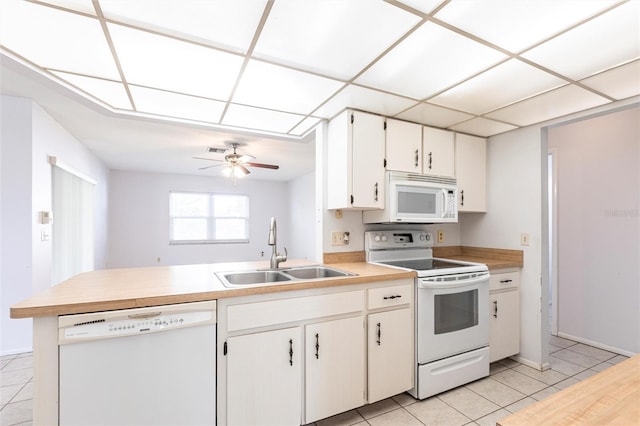 kitchen featuring light countertops, light tile patterned flooring, a sink, white appliances, and a peninsula