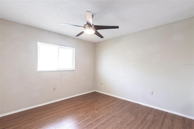 spare room with a textured ceiling, baseboards, and wood finished floors