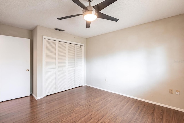 unfurnished bedroom featuring a closet, visible vents, baseboards, and wood finished floors