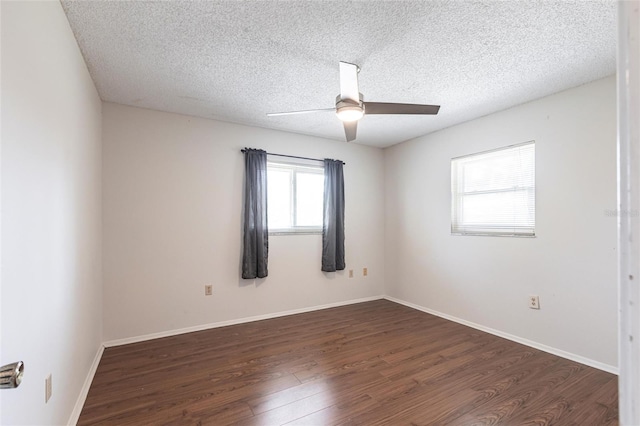 empty room featuring a ceiling fan, dark wood-style flooring, a textured ceiling, and baseboards