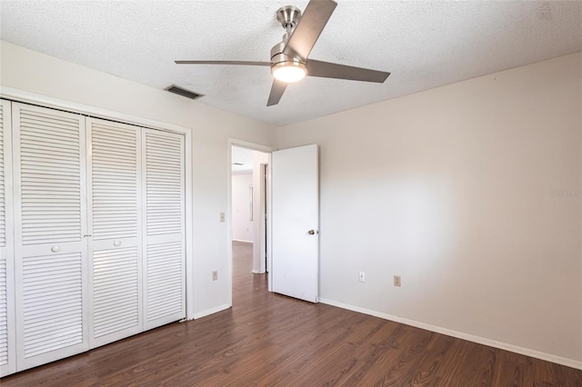 unfurnished bedroom with a textured ceiling, a ceiling fan, baseboards, a closet, and dark wood finished floors