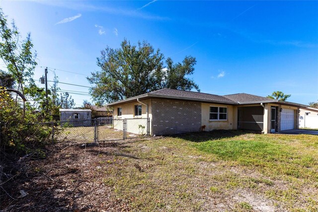 exterior space featuring an attached garage, brick siding, fence, a yard, and a gate