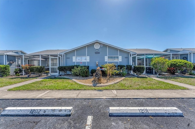 view of front facade with uncovered parking, a front yard, and a lanai