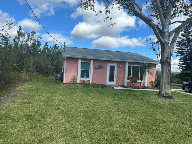 view of front of property with central air condition unit, a front lawn, and stucco siding