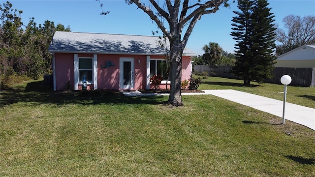 single story home featuring a shingled roof, fence, and a front lawn