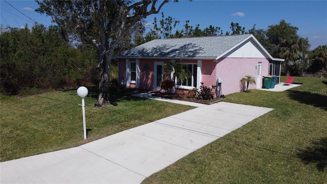 ranch-style house with roof with shingles, a front lawn, and stucco siding