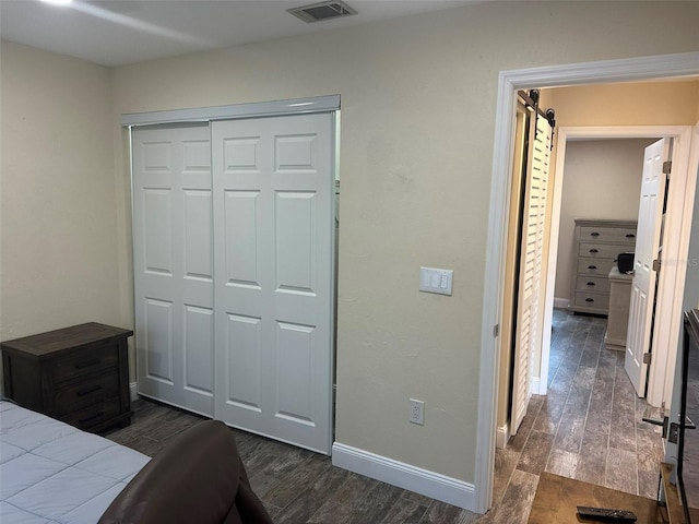 bedroom with dark wood-style floors, a closet, visible vents, and baseboards