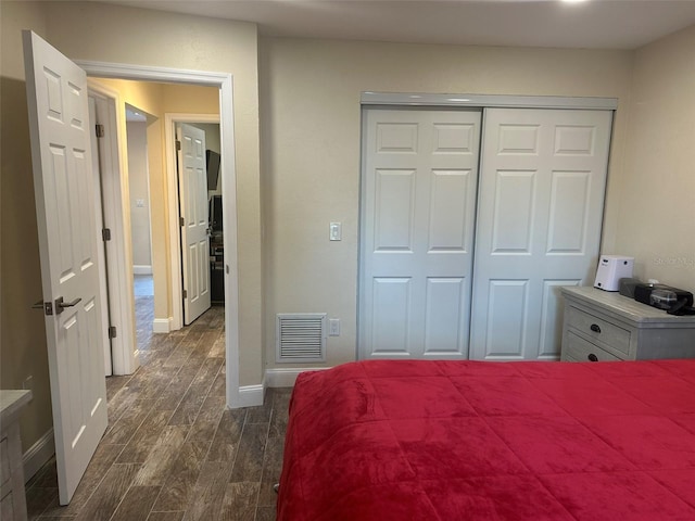 bedroom with baseboards, a closet, visible vents, and wood tiled floor