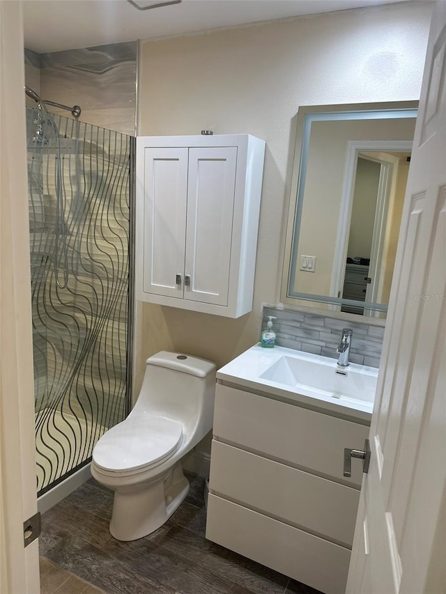 bathroom with tasteful backsplash, vanity, toilet, and wood finished floors