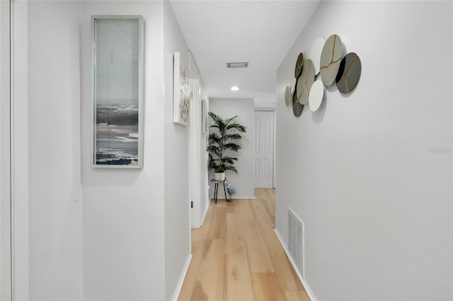 corridor featuring a textured ceiling and light wood-type flooring