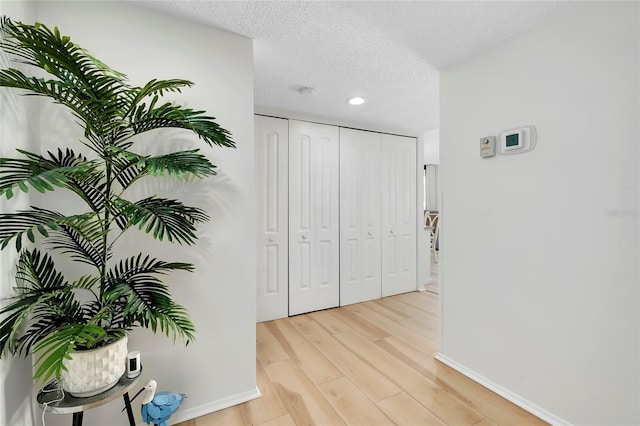 corridor with light hardwood / wood-style floors and a textured ceiling