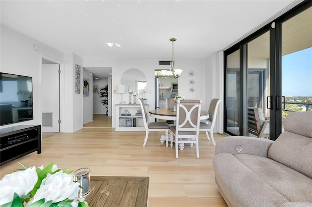 living room featuring expansive windows, a notable chandelier, and light wood-type flooring