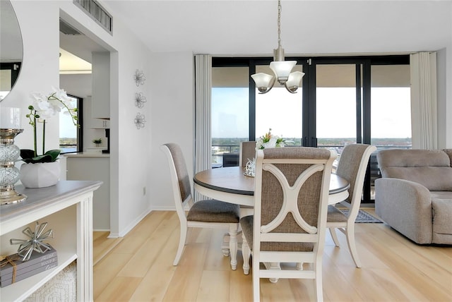 dining room featuring an inviting chandelier, wood-type flooring, and expansive windows