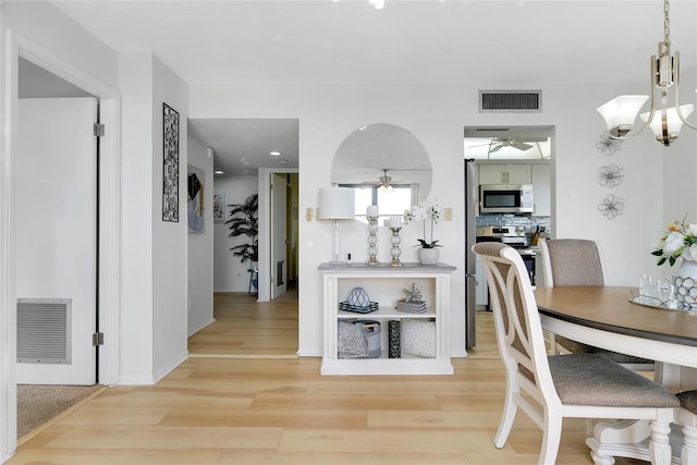 dining room featuring light hardwood / wood-style floors and ceiling fan with notable chandelier