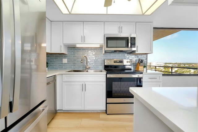 kitchen with white cabinetry, sink, backsplash, stainless steel appliances, and light wood-type flooring