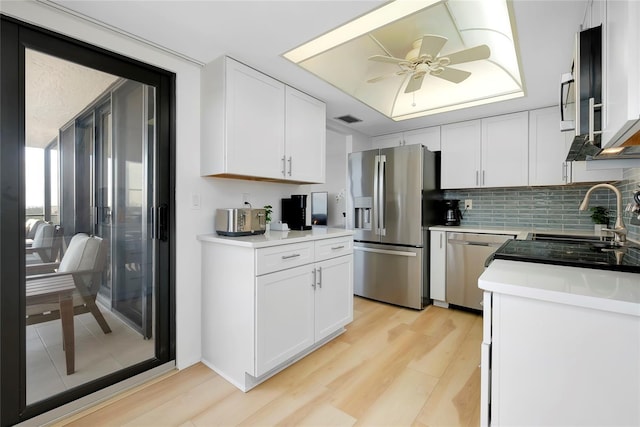 kitchen with light hardwood / wood-style flooring, a raised ceiling, white cabinets, and appliances with stainless steel finishes