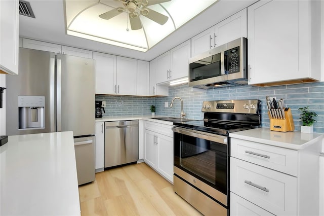 kitchen with stainless steel appliances, white cabinetry, and tasteful backsplash