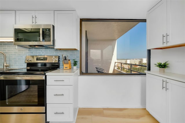 kitchen with white cabinetry, tasteful backsplash, light hardwood / wood-style flooring, and appliances with stainless steel finishes