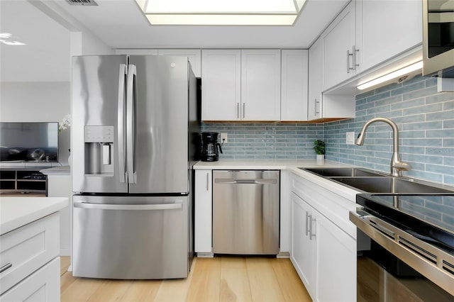 kitchen featuring tasteful backsplash, sink, white cabinets, and appliances with stainless steel finishes