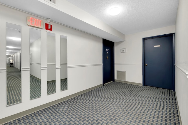 hallway with carpet flooring and a textured ceiling