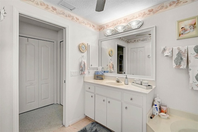 bathroom featuring vanity, ceiling fan, and a textured ceiling