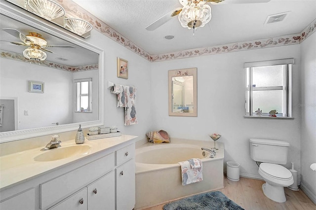 bathroom featuring vanity, a bath, ceiling fan, and toilet