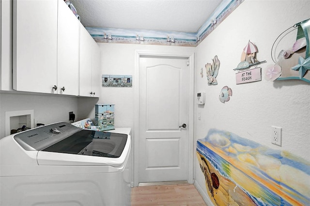 clothes washing area featuring cabinets, light hardwood / wood-style floors, a textured ceiling, and washing machine and clothes dryer