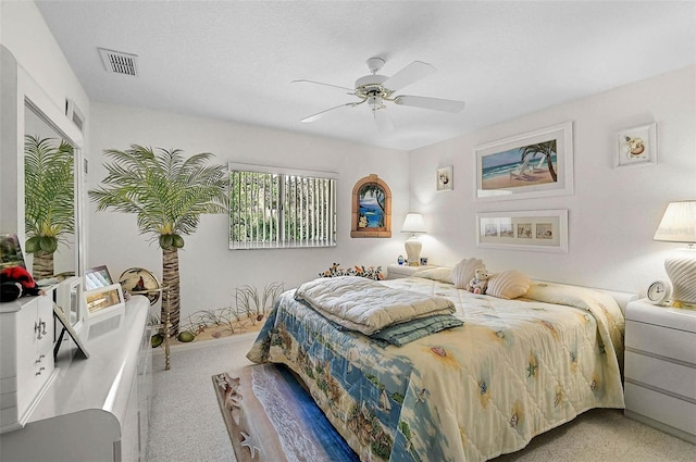 carpeted bedroom featuring ceiling fan and a textured ceiling