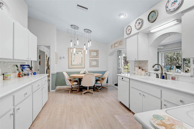 kitchen with white cabinetry, hanging light fixtures, white dishwasher, and sink