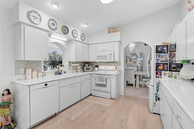 kitchen featuring white cabinetry, sink, backsplash, and white appliances