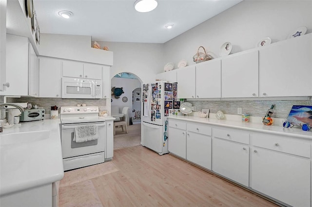 kitchen featuring light wood-type flooring, backsplash, white cabinets, and white appliances