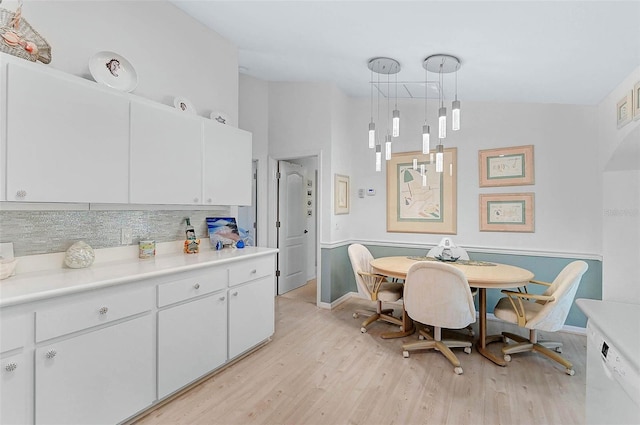 kitchen with white cabinetry, lofted ceiling, light hardwood / wood-style floors, and pendant lighting