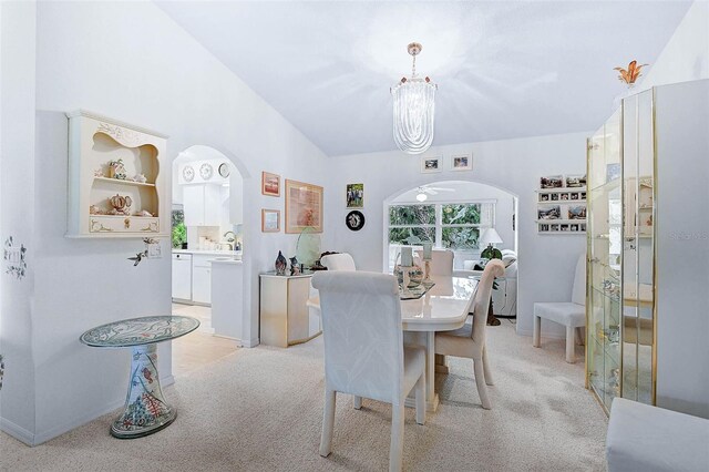 dining area with lofted ceiling, light carpet, and a notable chandelier