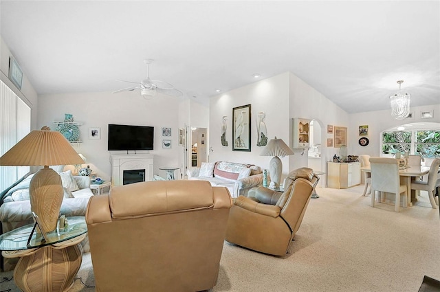 living room with vaulted ceiling, ceiling fan with notable chandelier, and light carpet