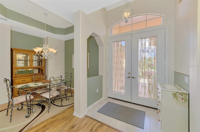 entryway featuring french doors, a chandelier, and light wood-type flooring