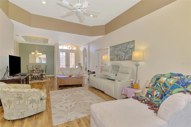 living room with french doors, ceiling fan, light wood-type flooring, and a tray ceiling