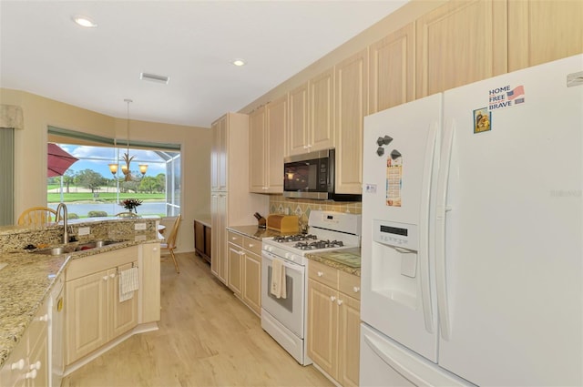 kitchen featuring sink, white appliances, hanging light fixtures, light stone countertops, and decorative backsplash