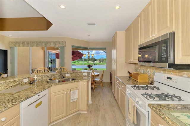 kitchen featuring sink, light brown cabinetry, and white appliances