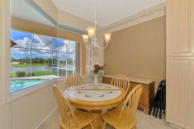 dining room with a water view, an inviting chandelier, and light wood-type flooring