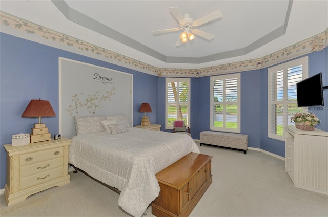 carpeted bedroom featuring a tray ceiling and ceiling fan