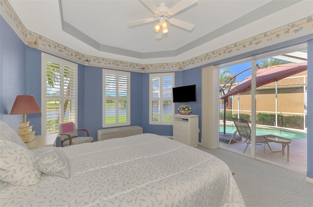 carpeted bedroom featuring a raised ceiling, access to exterior, and ceiling fan